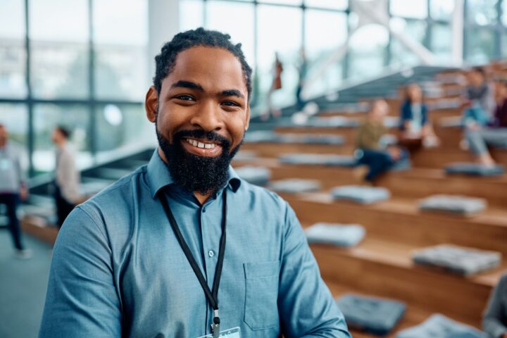 Happy black businessman attending an education event in convention center and looking at camera.